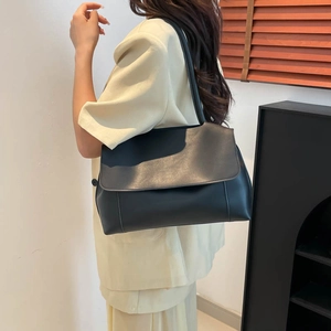 Minimalist black tote shoulder bag in matte leather worn by model for office commute