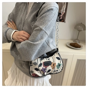 Detail of floral canvas underarm bag with black leather trim and chain shoulder strap