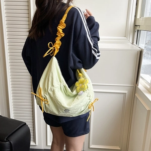 Light green nylon crossbody bag with yellow gathered strap and floral charm detail