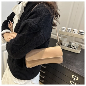 Détail d'un sac baguette en cuir verni beige avec une finition brillante et un rabat