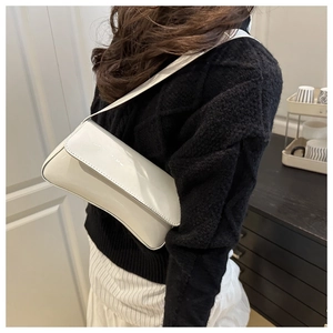 Mannequin portant un sac baguette en cuir verni blanc à l'épaule pour un style urbain