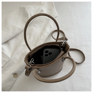 Detailed top view of brown leather bucket bag showing dual zipper pockets and phone storage