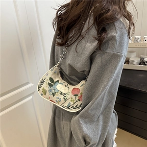 Floral tapestry baguette bag with silver chain strap worn by a model in a cozy setting