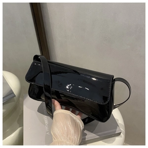 Détail d'un sac à bandoulière en cuir verni noir brillant avec un design à rabat chic