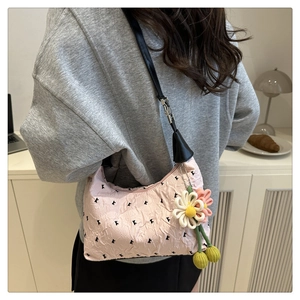 Close-up of pink ruched shoulder bag with letter prints and floral charm details