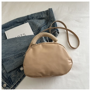 Sac à main beige semi-circulaire sur tissu blanc avec livres et veste en jean chic