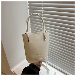 Detail of cream beige bucket bag with FASHION lettering and silver metal hardware accents
