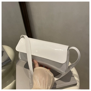Gros plan du sac bandoulière en cuir verni blanc avec finition brillante et rabat moderne