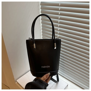 Close-up of black leather bucket bag featuring silver FASHION lettering and twin handles