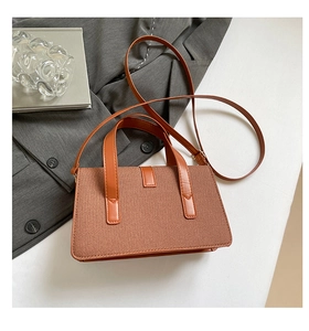 Close-up of brown textured woven handbag featuring faux leather trim and strap detail
