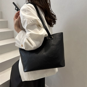 Minimalist large black leather tote bag for women shown on a modern white staircase