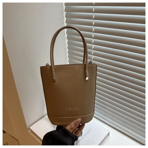 Close-up of camel leather bucket bag with silver Fashion lettering and slim handle