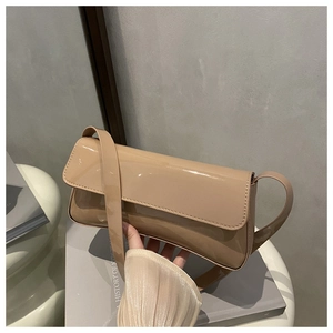 Détail d'un sac baguette en cuir verni beige brillant porté par un mannequin