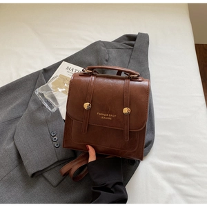 Detail of a brown vintage PU leather backpack with gold buckles and a top handle