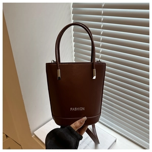 Detailed view of brown leather bucket bag with silver Fashion lettering and top handle