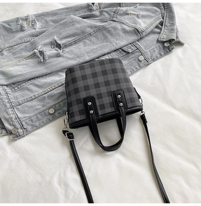 Nahaufnahme der Schachbrett-Handtasche mit Ledergriffen und silbernen Nieten auf Denim