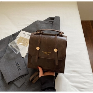 Detail showing vintage dark brown PU leather texture and gold metal buckle on the backpack