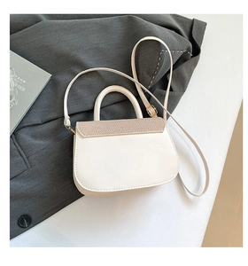 Detail of cream leather handbag with woven texture flap on a grey blazer background