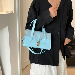 Borsa a tracolla patchwork azzurro e bianco con chiusura dorata su una modella