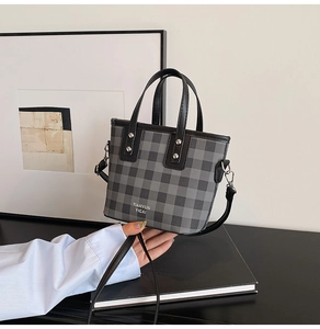 Detail der Mini-Beuteltasche mit Karomuster, Ledergriffen und silbernen Nieten