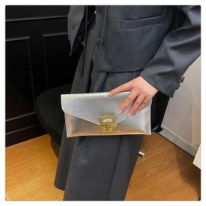 Détail de la pochette enveloppe argentée avec fermoir géométrique doré et texture métal