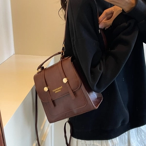 Vintage brown leather backpack with gold rivets and top handle shown as a crossbody bag