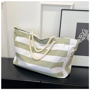 Close-up of green striped canvas tote bag with thick rope handles and metal eyelets