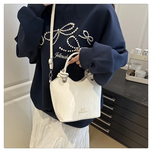 Détail du sac seau blanc brillant avec poignée perlée et logo doré élégant
