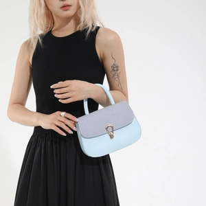 Light blue crossbody bag with gold droplet lock and textured flap shown by a model
