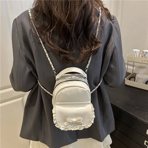 Mini cream bow backpack with lace trim shown on a model in a stylish indoor setting
