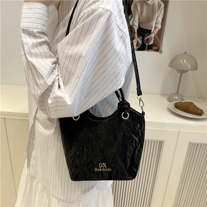 Sac à bandoulière noir plissé moderne avec logo doré pour un style de transport minimaliste