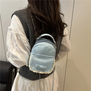 Light blue mini backpack with bow and lace detail worn by a model on a grey background