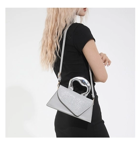 Détail du sac à main brillant avec poignée en métal liquide et bandoulière en cuir gris