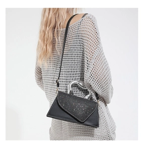 Détail du rabat pailleté noir du sac en cuir avec poignée en métal et coutures