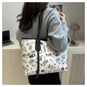 Dettaglio di una grande borsa tote bianca con graffiti neri sulla spalla di una modella