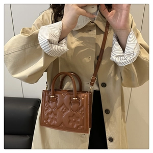 Close-up of brown embossed leather handbag with flower pattern and adjustable shoulder strap