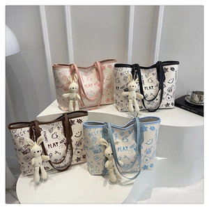 Detail view of printed canvas tote bags with graffiti patterns and plush rabbit charms