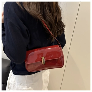 Close-up of bright red patent leather shoulder bag with a gold rectangular metal buckle