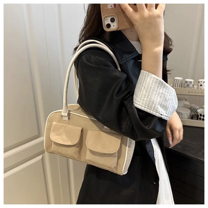 Detail of a beige suede crossbody bag with utility pockets and white leather piping