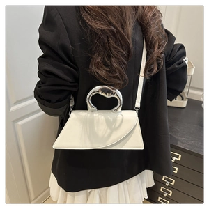 Minimalist white trapezoid handbag featuring a unique silver fluid metal handle for a chic look