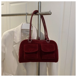 Detail view of burgundy suede handbag with two front pockets on a chrome hanger