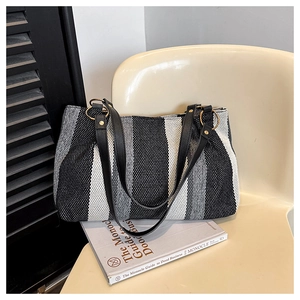 Detailed view of striped canvas tote bag with black leather handles and gold metal rings