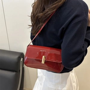 Glossy red patent leather shoulder bag with gold metal clasp on female model