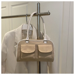 Detail of khaki shoulder bag with dual front pockets and white contrast stitching