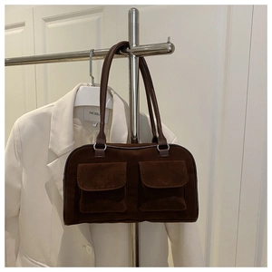Detail of dark brown suede handbag featuring dual front pockets and silver hardware