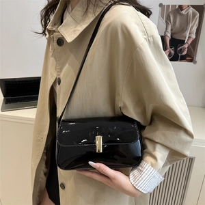 Glossy black patent leather square bag with gold buckle on trench coat model