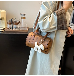 Sac Boston marron avec imprimé ours et breloque, présenté dans un décor de café chic