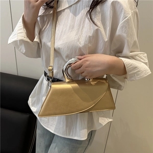 Minimalist gold asymmetric handbag with unique silver curved metal handle and slim strap