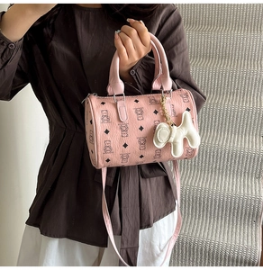 Sac Boston rose avec motifs d'ours et charm chien tenu à la main