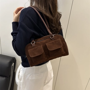 Brown suede shoulder bag with dual front pockets and zipper closure for casual wear